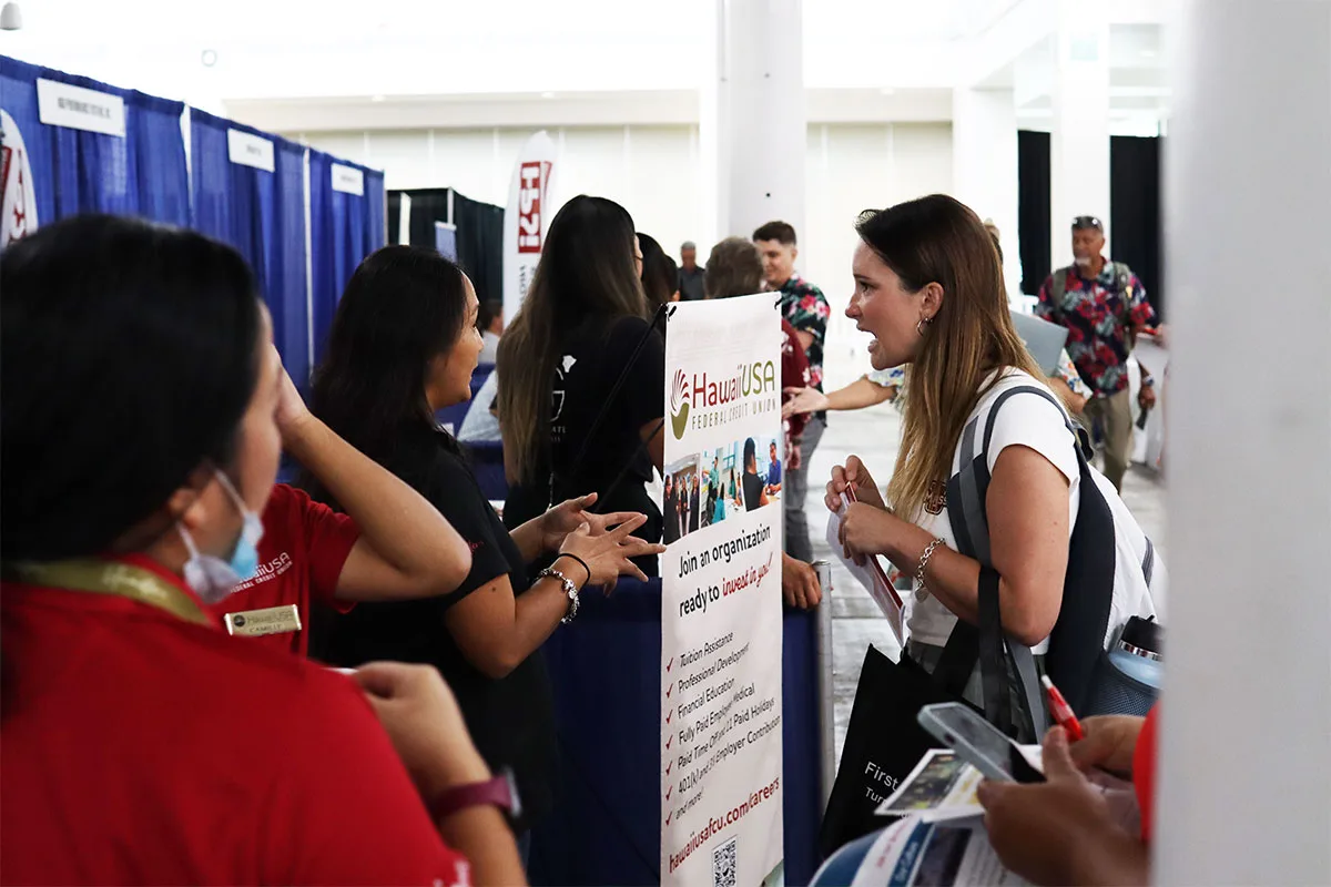 A job seeker talking with recruiters at the HawaiiUSA Federal Credit Union booth