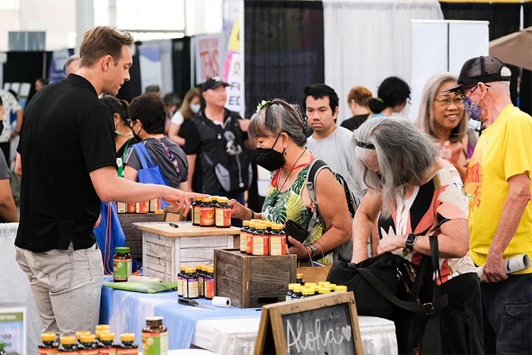 Attendees sampling products at an exhibitor booth on a busy expo floor